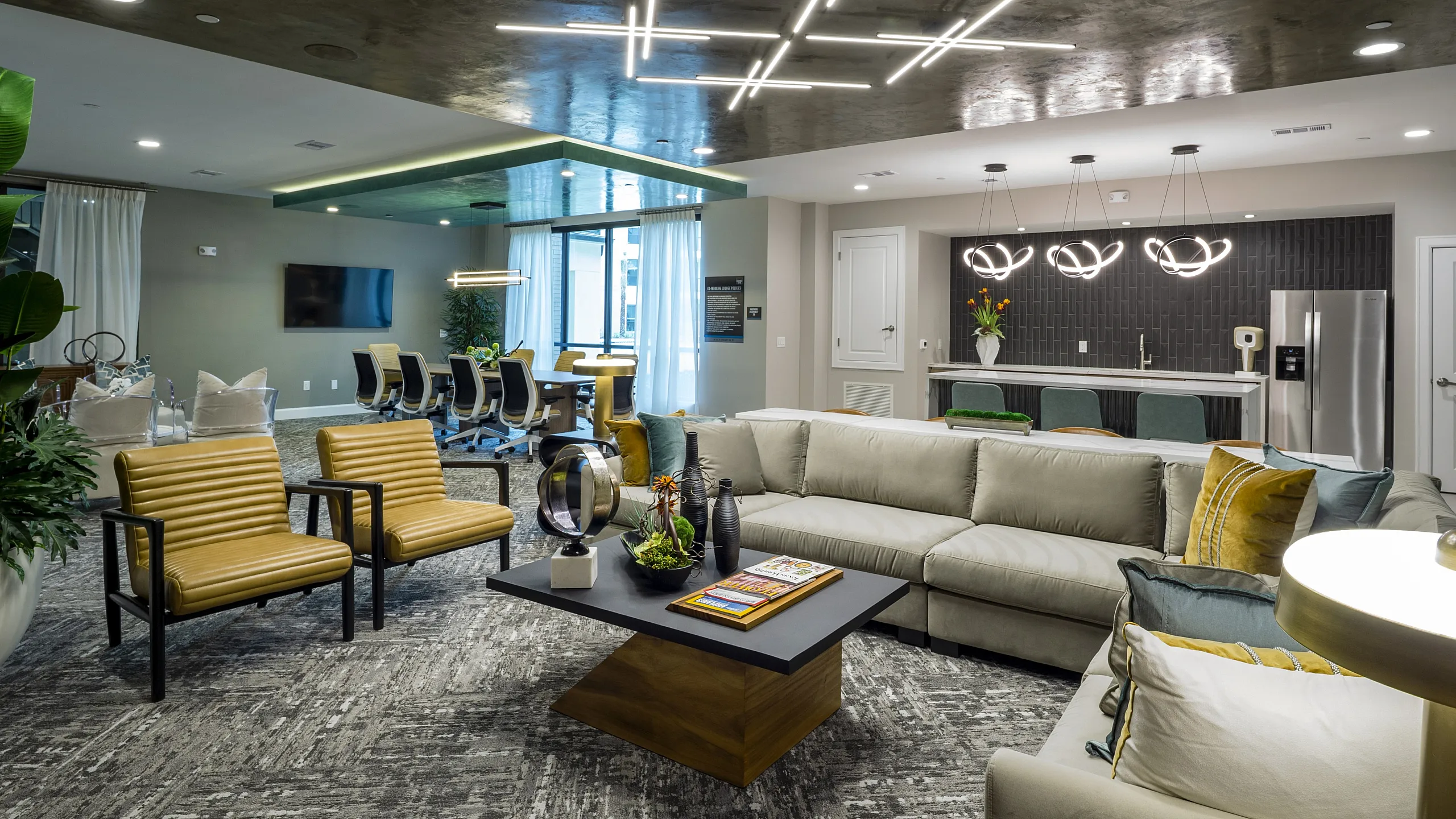Luxurious open-concept living space with modern seating, stylish lighting, and a sleek kitchen area ideal for entertaining.