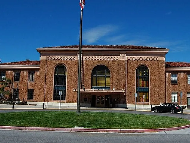 Charming brick building with grand arched windows, set against a bright blue sky, perfect for business opportunities.