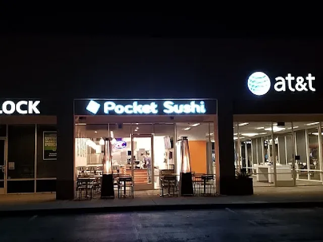 Vibrant night scene showcasing a modern strip mall with illuminated signs for H&R Block, Pocket Sushi, and AT&T, featuring inviting storefronts and ample parking.