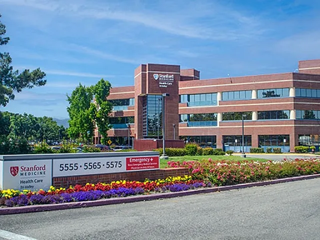 Modern commercial building with a brick facade, surrounded by vibrant landscaping and clear blue skies.