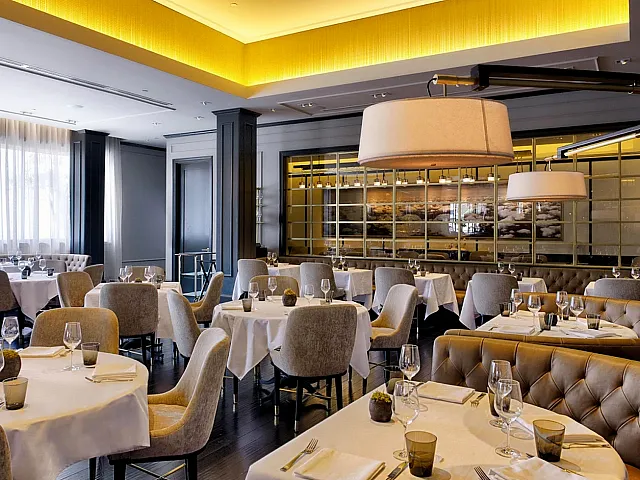 Elegant restaurant interior with modern lighting, stylish gray seating, and neatly set tables creating a sophisticated dining ambiance.