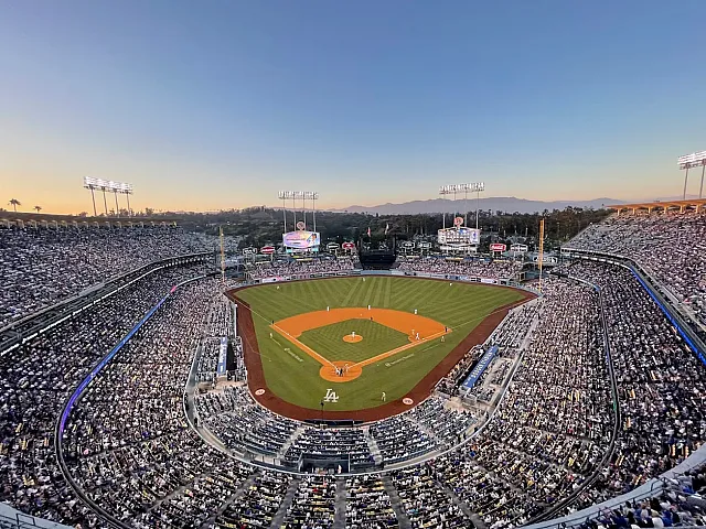 Stunning aerial view of a vibrant baseball stadium filled with enthusiastic fans under a clear evening sky.