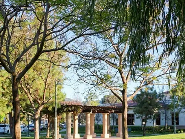 Serene outdoor view with lush greenery and elegant pergola, ideal for relaxation and enjoying nature.