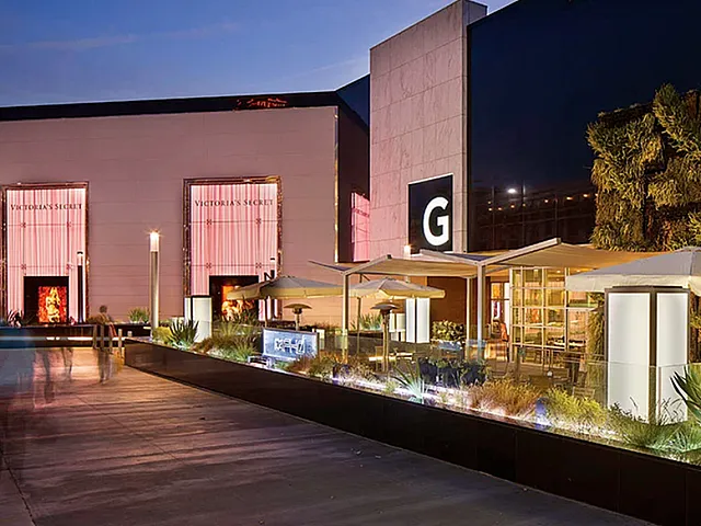 Chic urban commercial space with illuminated signage, lush vertical garden, and elegant outdoor seating.