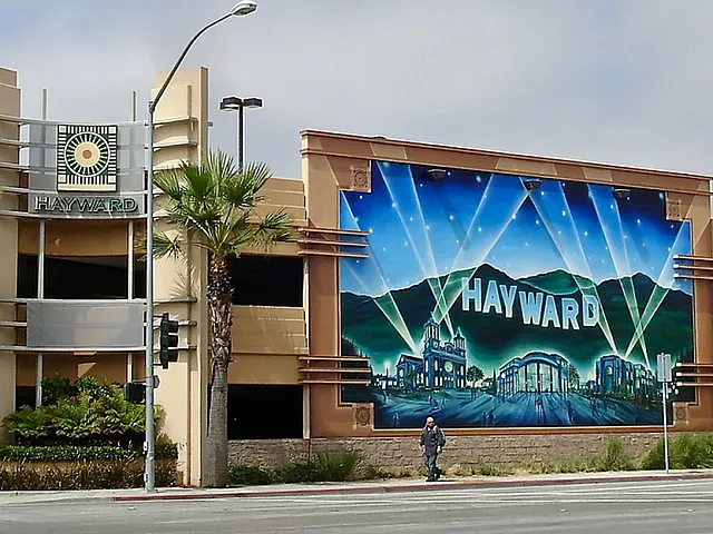 Vibrant street mural of Hayward featuring illuminated landmarks and lush palm trees, creating an inviting urban scene.