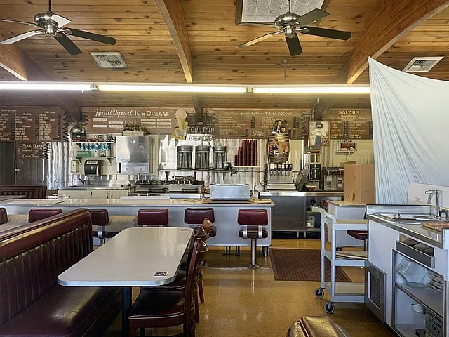 Charming retro-style ice cream parlor with wood-paneled ceiling, cozy booths, and vintage menu boards.