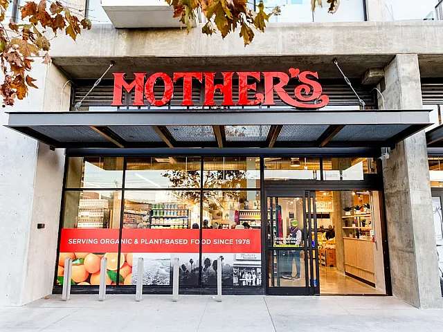 Welcoming entrance of Mother's Market, showcasing fresh and organic food offerings with vibrant signage and inviting glass storefront.