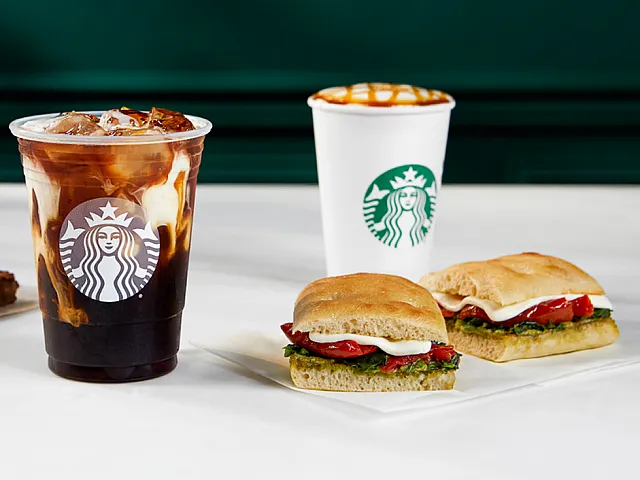 Delicious Starbucks spread featuring an iced coffee, caramel-topped hot beverage, freshly made sandwich, and rich chocolate brownie.