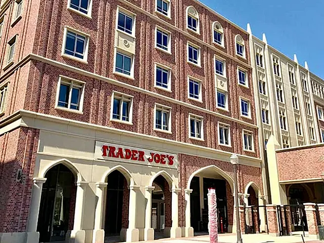 Charming brick facade of an upscale urban apartment complex with ground-floor retail space, featuring decorative arches and modern windows.