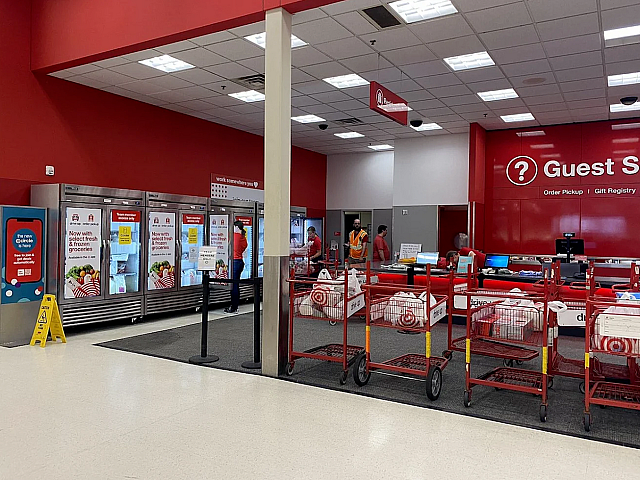 Vibrant retail area featuring customer service desks, colorful carts, and stocked grocery pickup section.