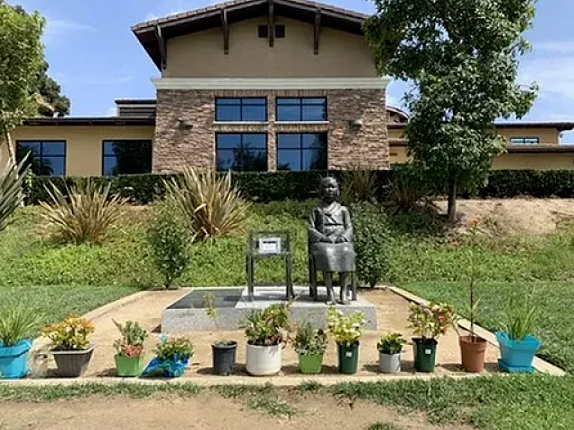 Charming community garden adorned with colorful potted plants and a striking sculpture, set against a modern building backdrop.
