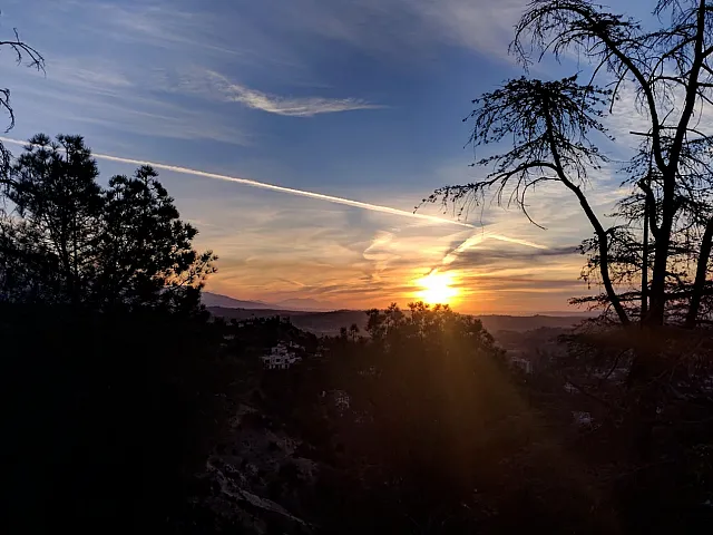 Breathtaking sunset view over a tranquil landscape with silhouetted trees and a vibrant sky.