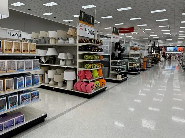 Bright, spacious retail aisle featuring decorative lamps, cozy pillows, and festive pumpkin decor.