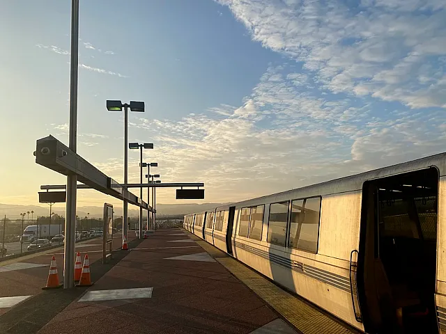 Vibrant sunrise at a modern train station with sleek silver train, promising urban connectivity and travel convenience.