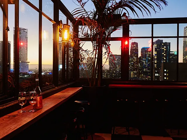 Chic urban bar with panoramic cityscape views, ambient lighting, and stylish seating, perfect for a sunset drink.