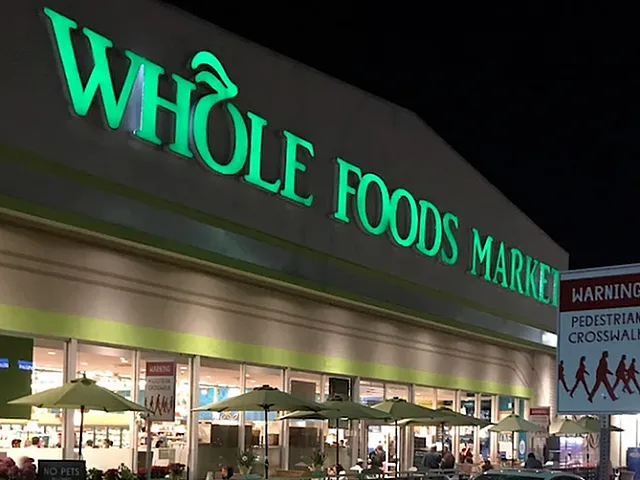 Inviting Whole Foods Market facade at night with illuminated signage, welcoming entrance, and bustling parking area.