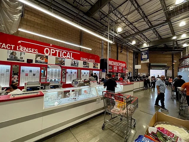 Bustling optical department featuring comprehensive eyewear displays and customer service counters in a spacious retail environment.