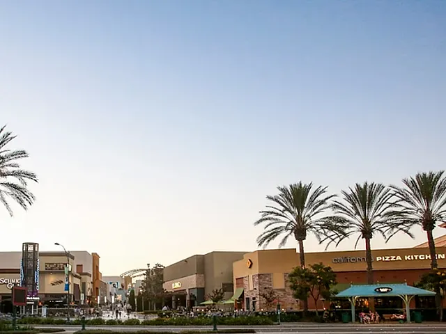 Vibrant shopping district at sunset, lined with tall palm trees and bustling restaurants, offering a lively atmosphere.