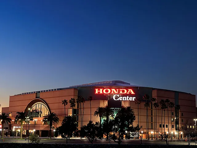 Vibrant evening view of the Honda Center illuminated against a twilight sky, surrounded by elegant palm trees.