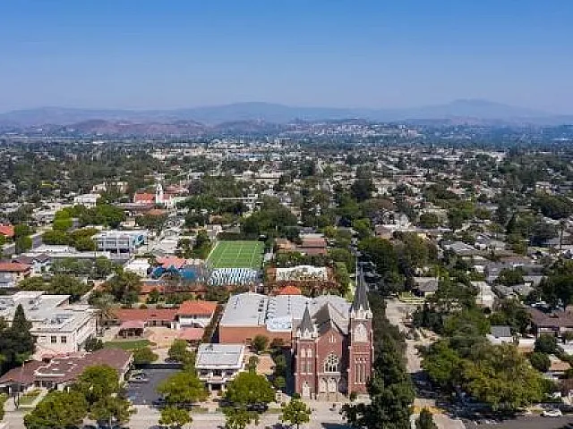 Breathtaking aerial view of a picturesque suburban neighborhood with lush greenery and distant mountain vistas.