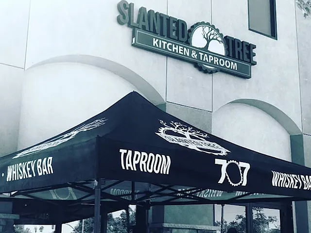 Inviting exterior of Slanted Tree Kitchen & Taproom with modern canopy promoting a vibrant whiskey bar and taproom atmosphere.