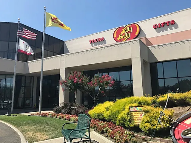 Inviting entrance to a well-known candy factory featuring bright landscaping and national flags, perfect for tours and gifts.