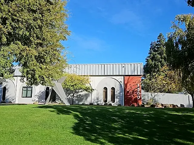 Modern architectural building with a sleek design set against a vibrant green lawn under a clear blue sky.