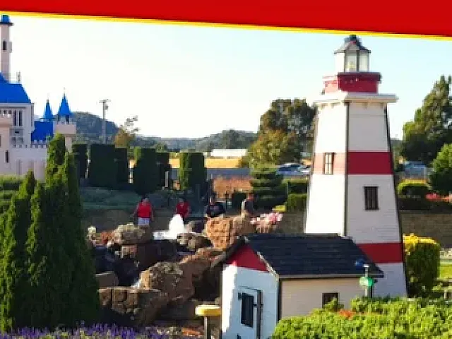 Charming landscaped park with a whimsical castle and lighthouse surrounded by vibrant gardens, perfect for family fun and exploration.