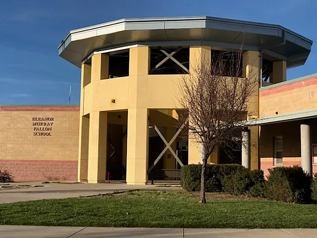 Contemporary school building with a unique architectural design, featuring a round structure and modern elements amidst a clear blue sky.