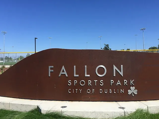 Modern entrance sign for Fallon Sports Park, set against a clear blue sky in the City of Dublin, showcasing a vibrant outdoor sports complex.