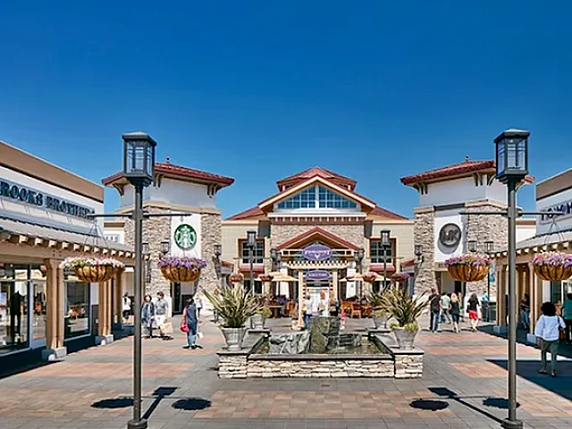 Vibrant outdoor shopping plaza with designer stores, charming architecture, and welcoming atmosphere under a clear blue sky.