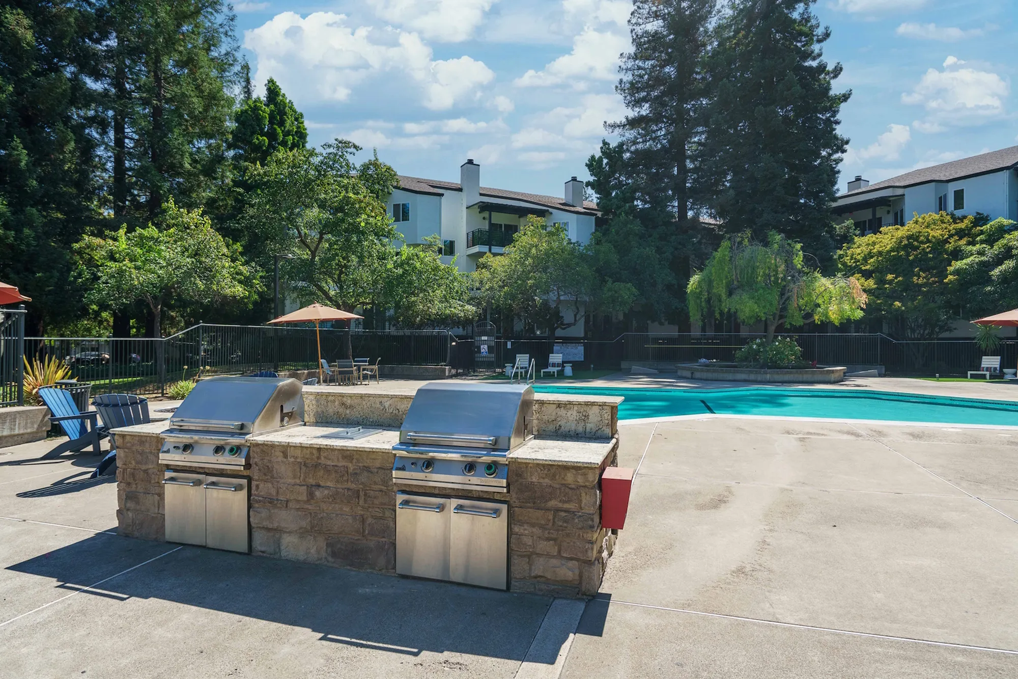 Scenic apartment pool area with BBQ and lush greenery