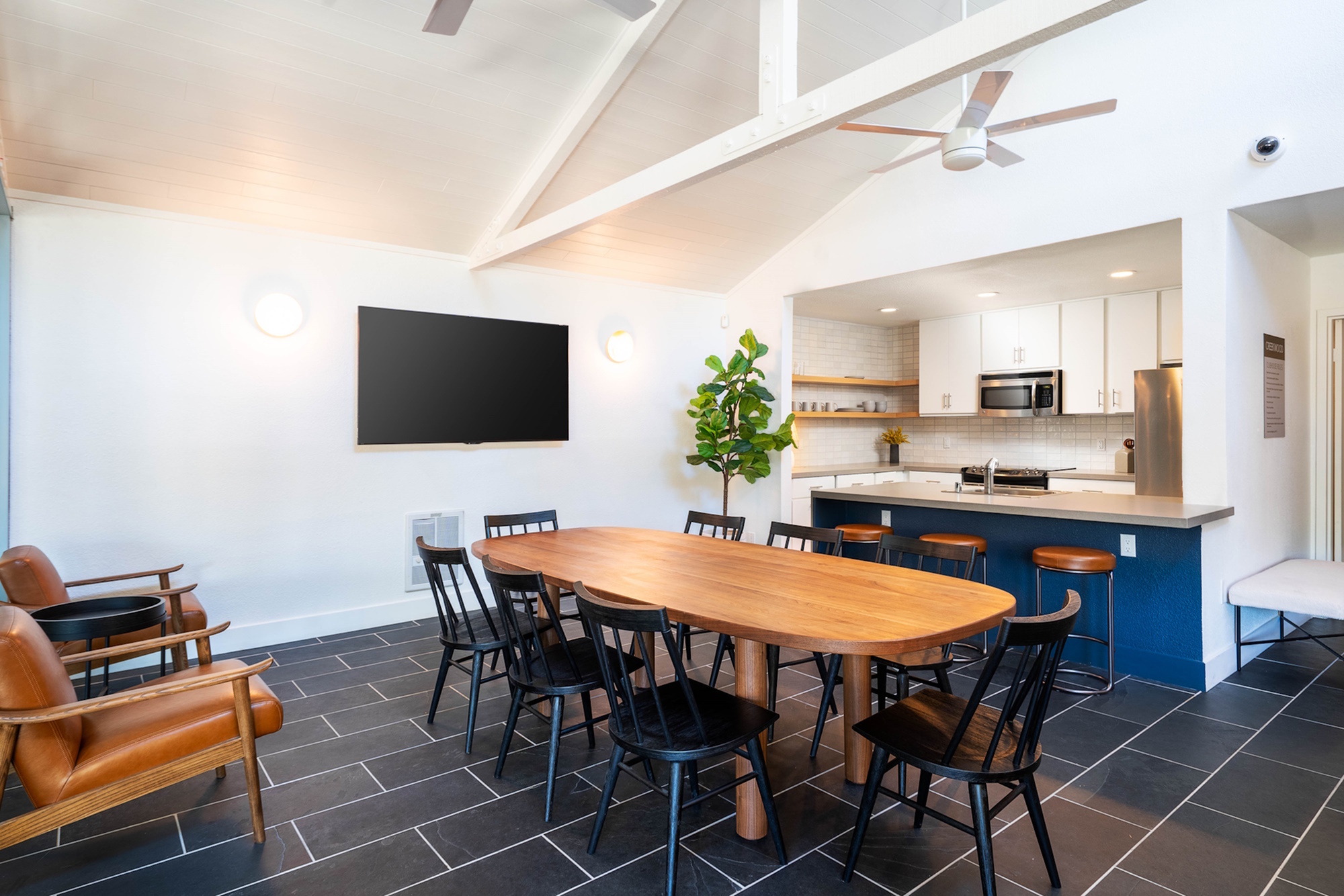 Spacious open-concept dining area with a wooden table, sleek black chairs, and a modern kitchen.