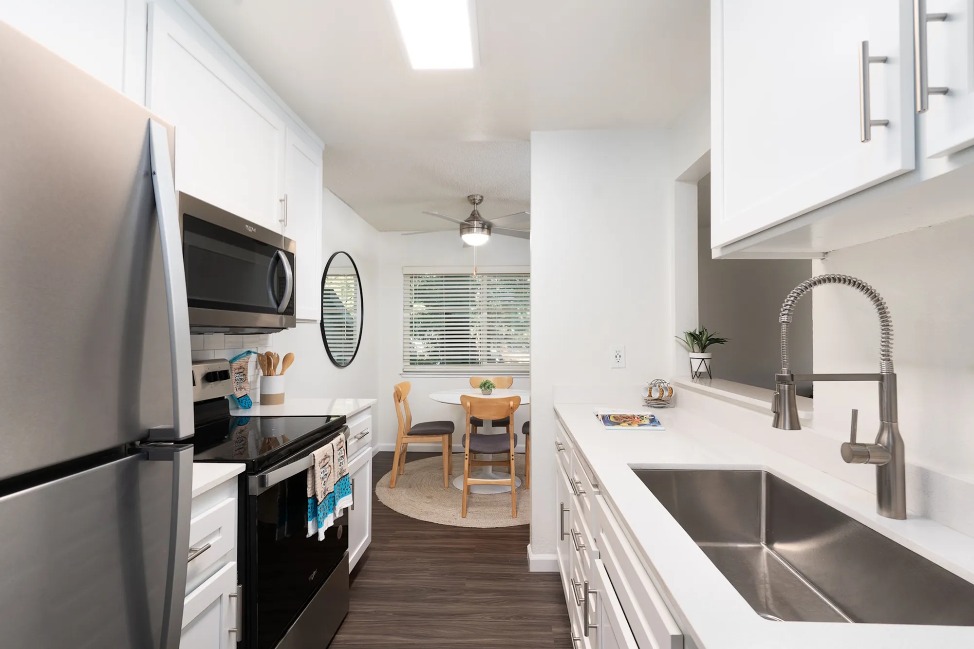 Contemporary kitchen with stainless steel appliances, sleek countertops, white cabinets, and a cozy dining nook.