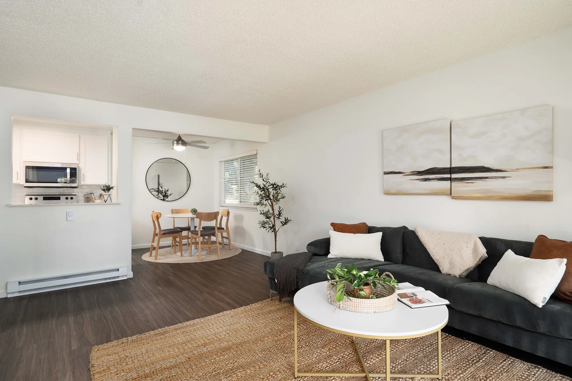 Chic living room with dark plush sofa, white coffee table, and open kitchen view.