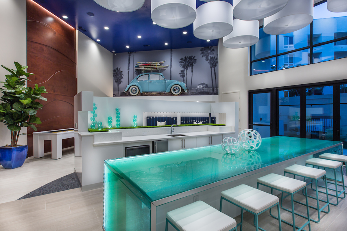 Resident club room with lounge seating, catering kitchen for resident events, dining table, pool table, multiple seating and TV viewing areas