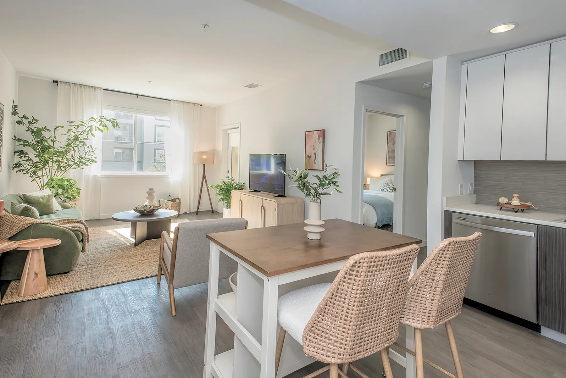 Chic modern apartment living room with natural light, cozy seating, and elegant decor, leading to a stylish kitchen.