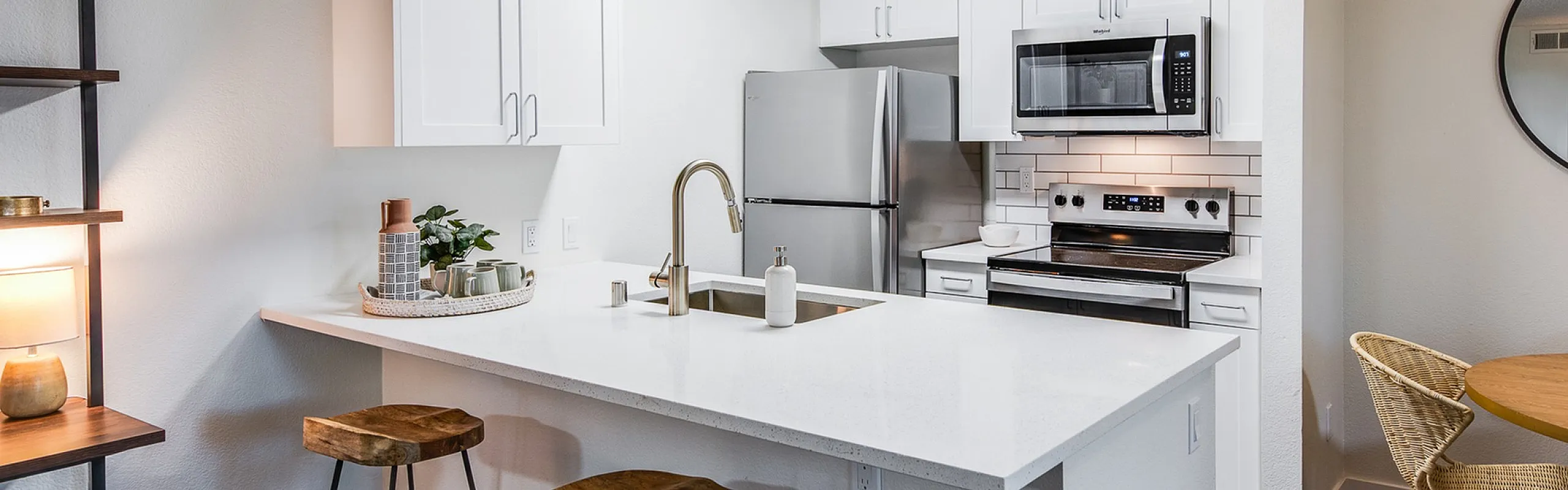 Modern kitchen with sleek white cabinets, stainless steel appliances, and a cozy breakfast bar with wooden stools.