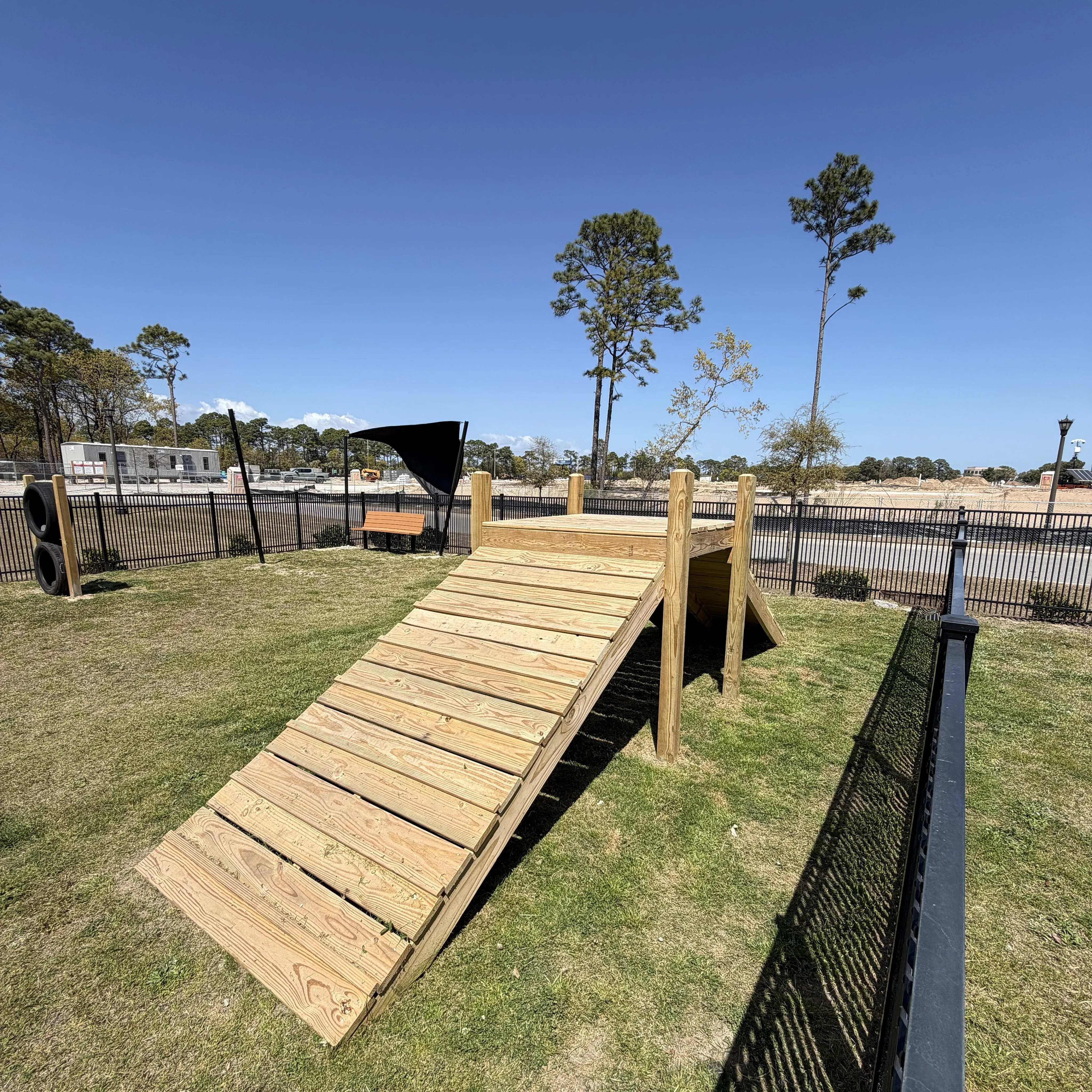 Charming outdoor space featuring a wooden ramp amid lush green grass, perfect for community enjoyment, under a clear blue sky.