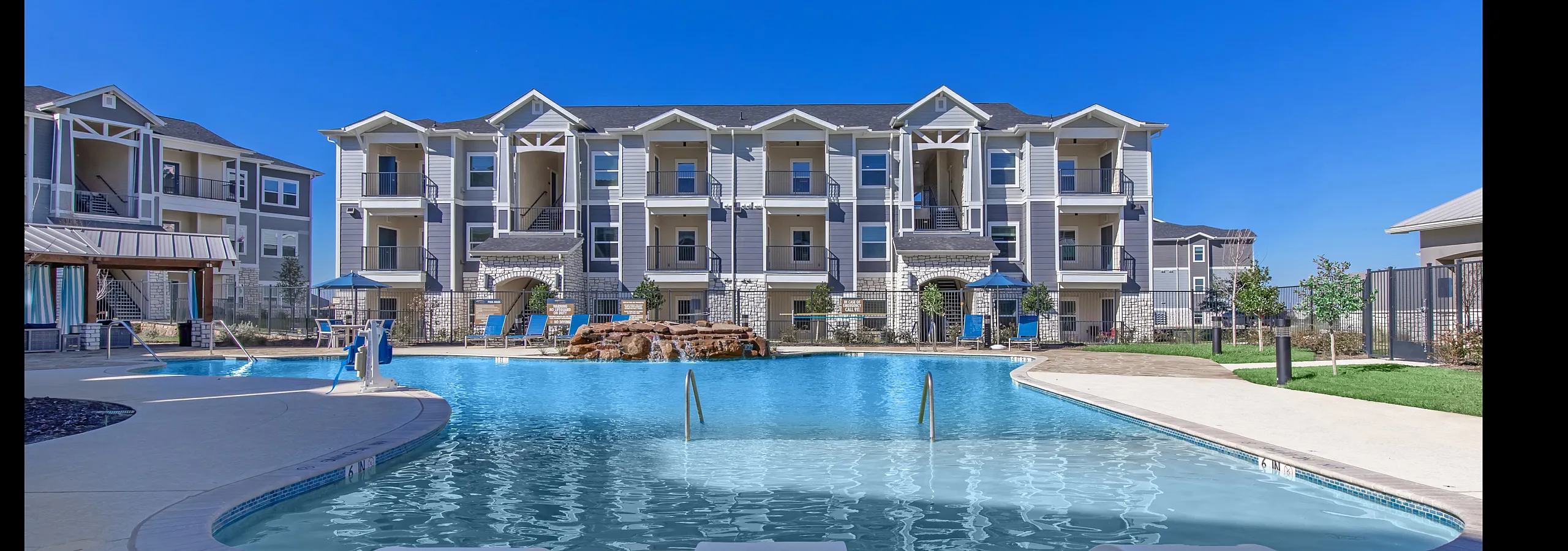 Stunning apartment complex with a large, sparkling swimming pool surrounded by modern architecture.