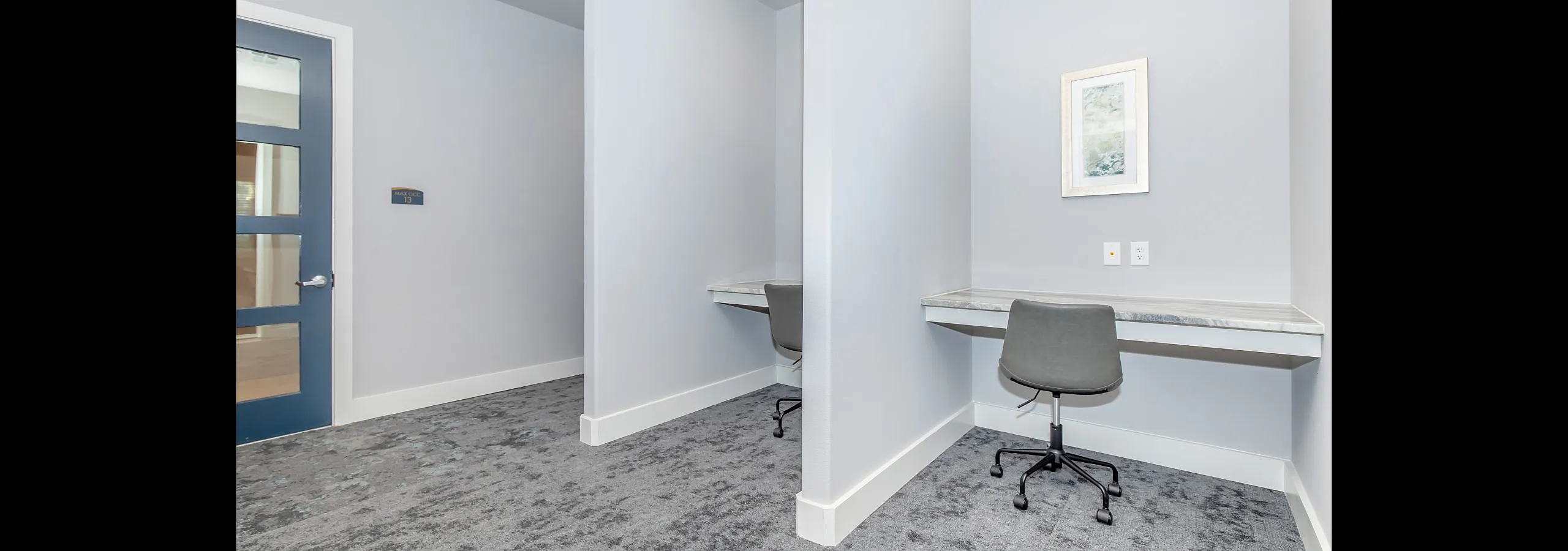 Contemporary office nook featuring two minimalist workstations with sleek chairs and modern light grey decor.