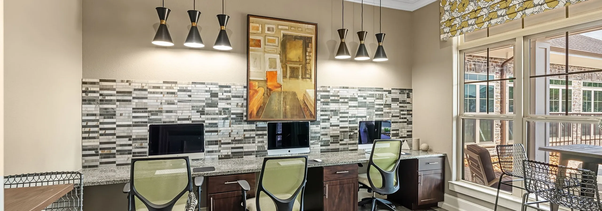 Inviting office space with modern design featuring sleek desks, stylish chairs, artistic lighting, and a large window for natural light.