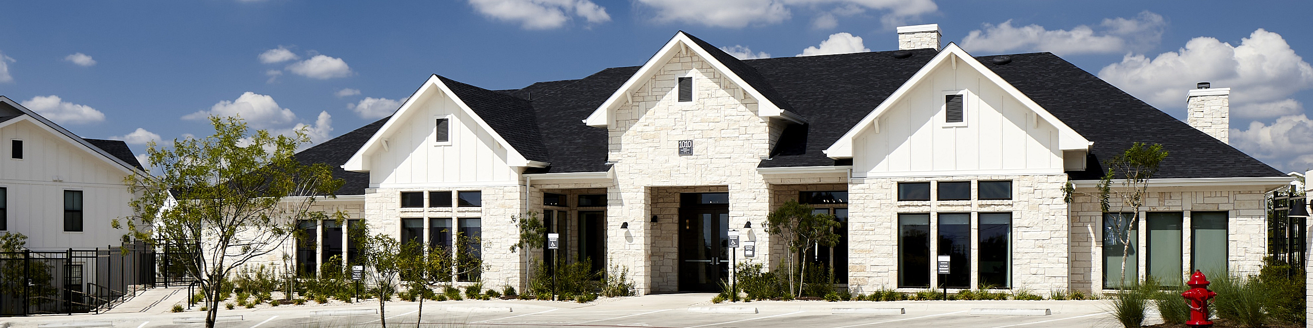 Charming white stone building with a dark roof, set against a clear blue sky, offering inviting curb appeal and modern architecture.