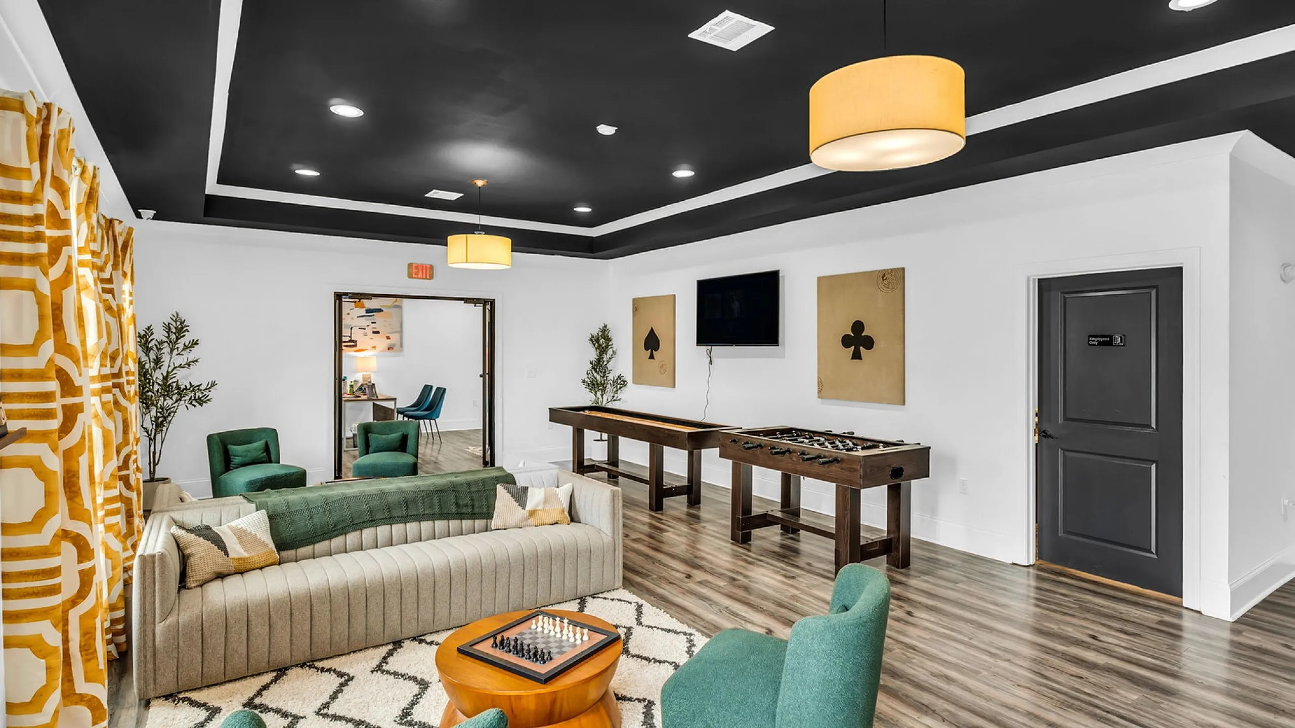 Elegant lounge with modern decor, featuring plush green seating, game tables, and stylish lighting accents.
