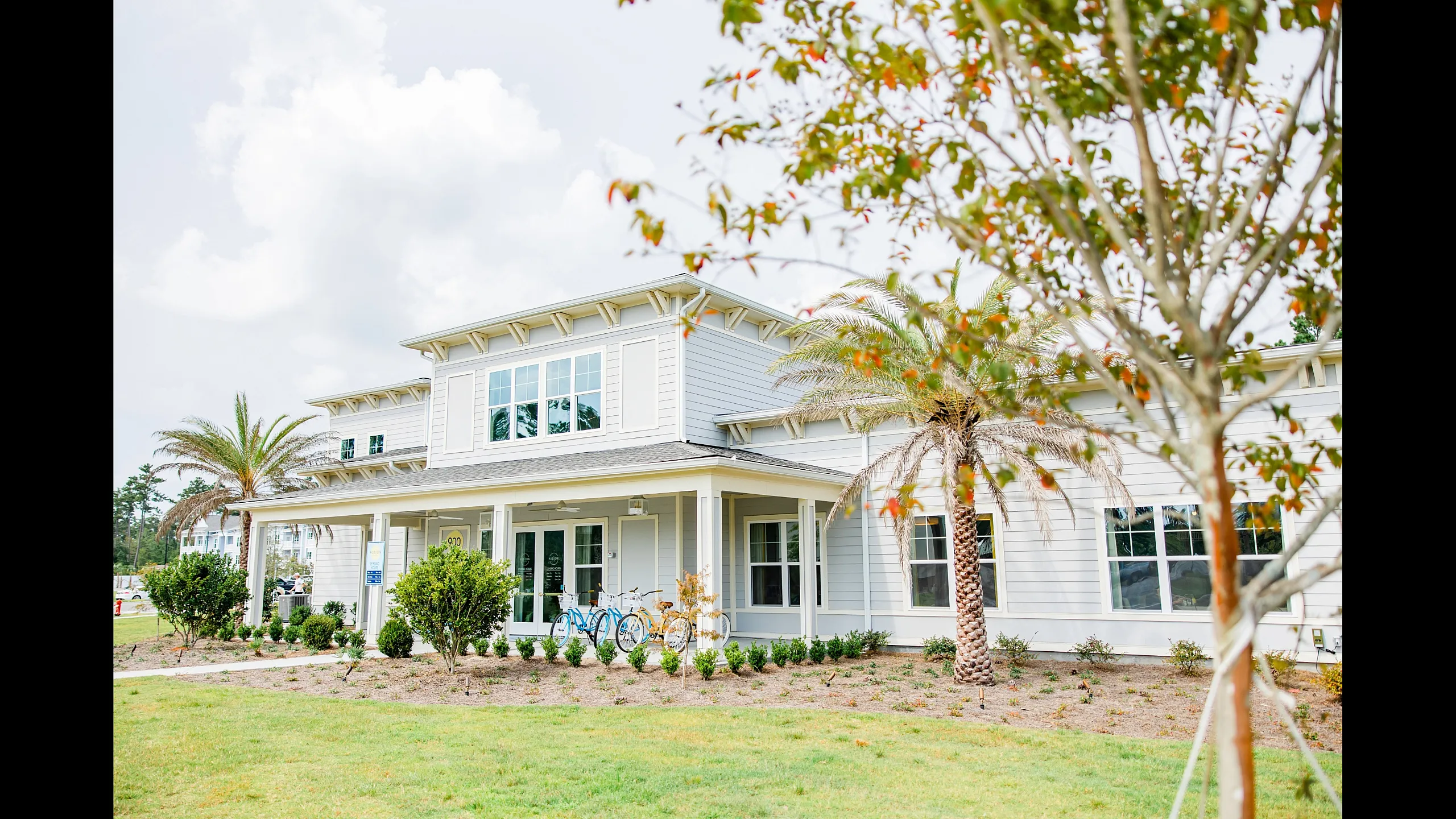 Charming two-story home with modern design, surrounded by lush landscaping and palm trees, offering a welcoming entrance and double-pane windows for natural lighting.