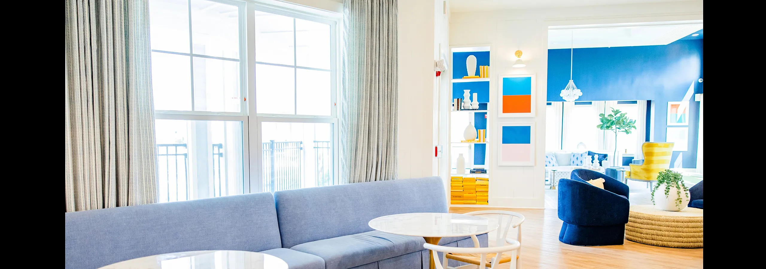 Bright, modern living area with blue sofas, artistic wall decor, and elegant wooden flooring, ideal for contemporary relaxation.