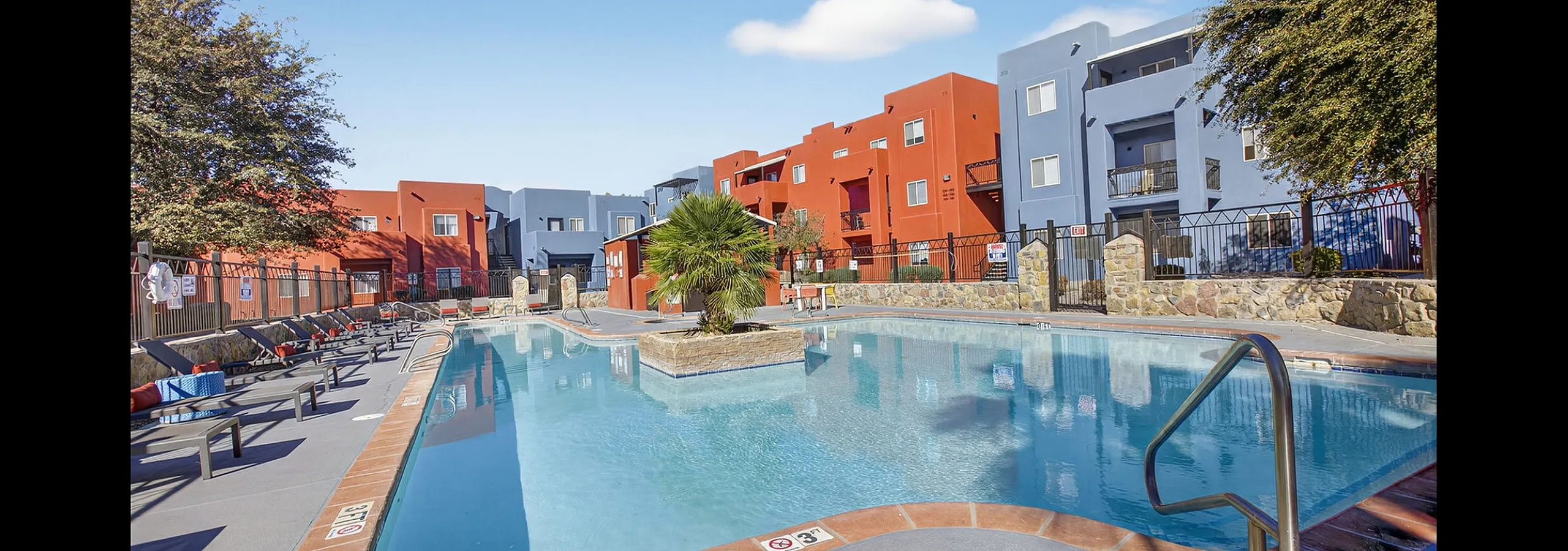 Vibrant apartment complex with a stunning pool surrounded by colorful buildings and lush greenery, perfect for relaxation and recreation.