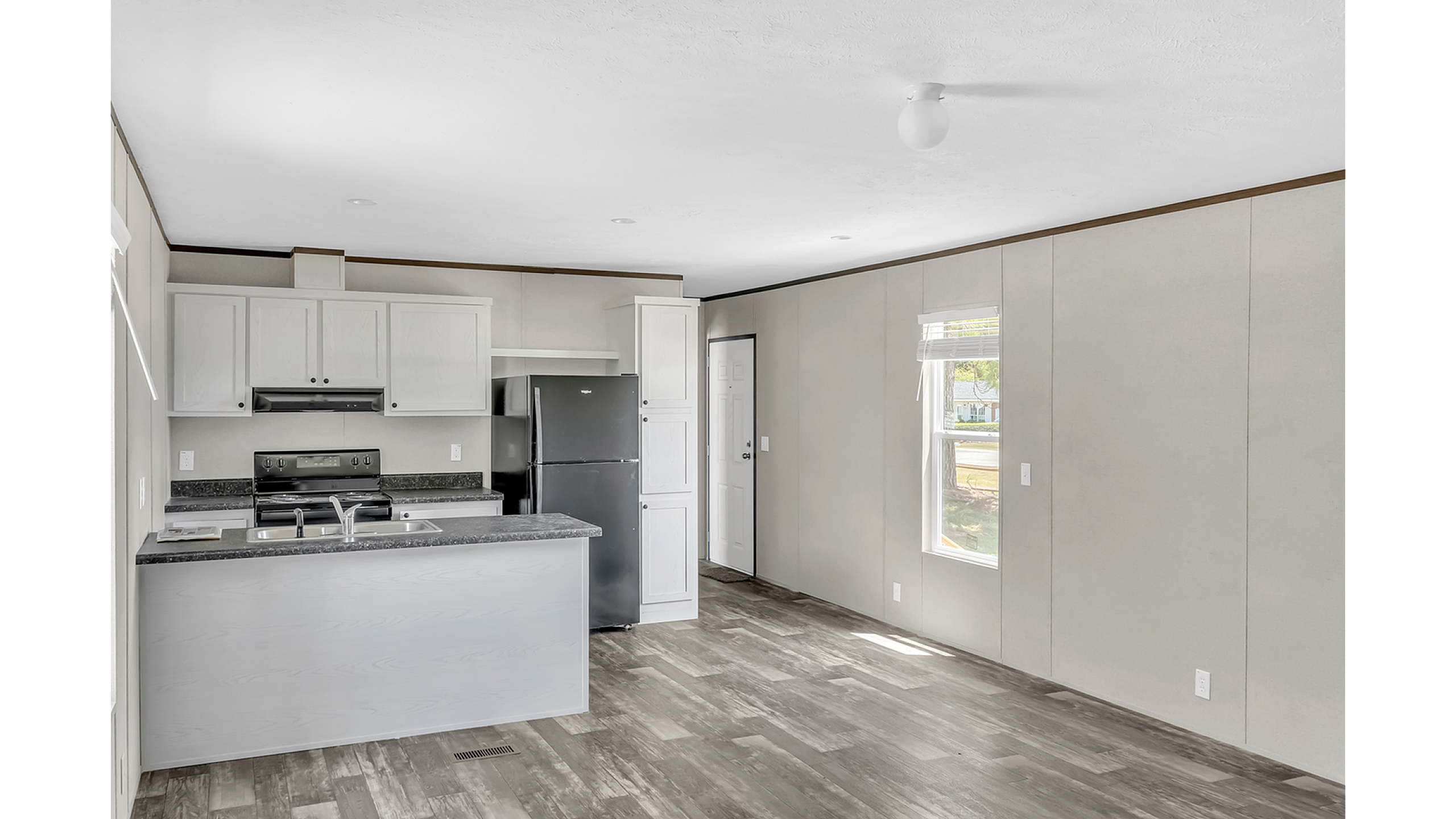 Bright and modern kitchen area with sleek cabinets, stainless steel appliances, and sunlit open floor space.
