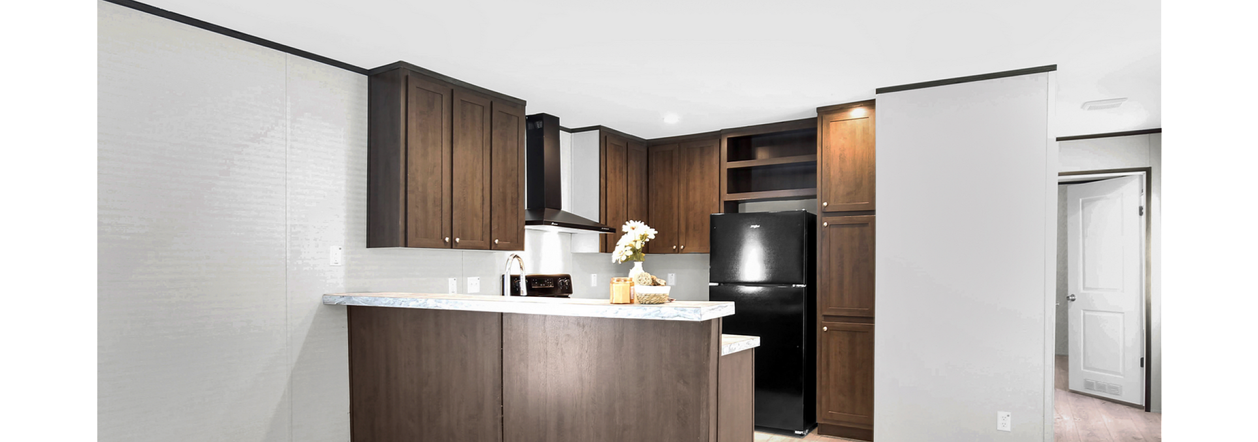 Contemporary kitchen with elegant wooden cabinets, sleek black appliances, and a stylish countertop, perfect for modern living.