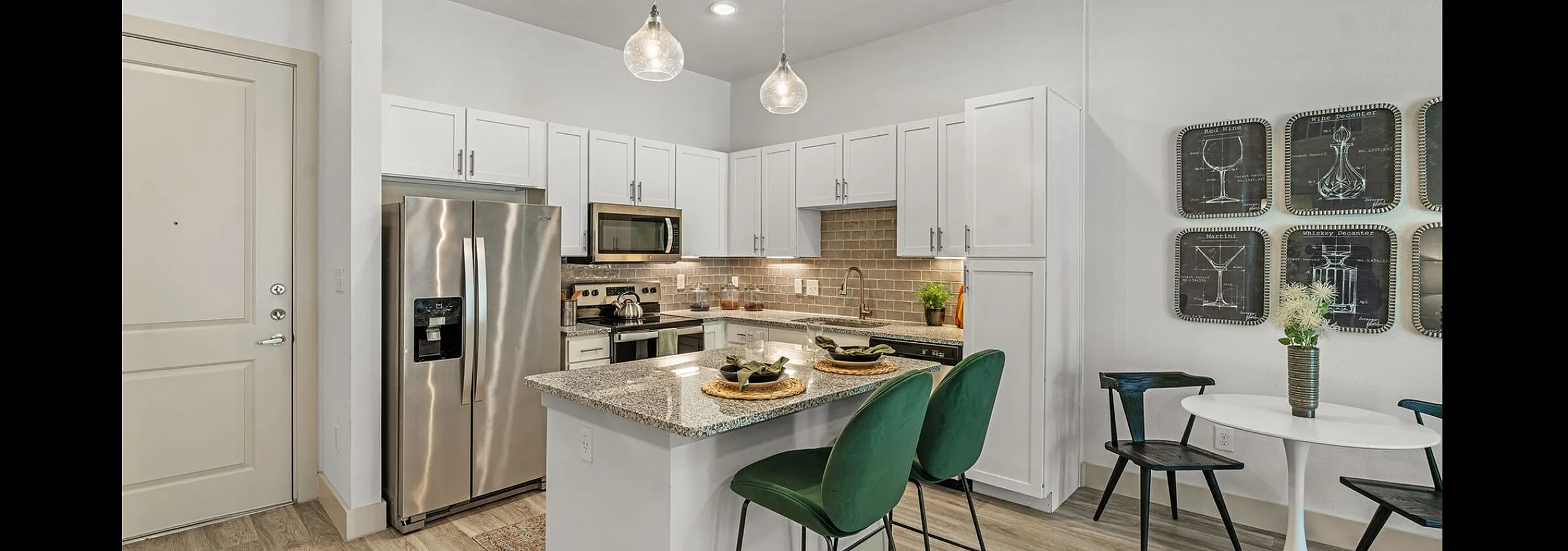 Modern kitchen with elegant white cabinetry, stainless steel appliances, and a sleek granite countertop breakfast bar accented by stylish green barstools.